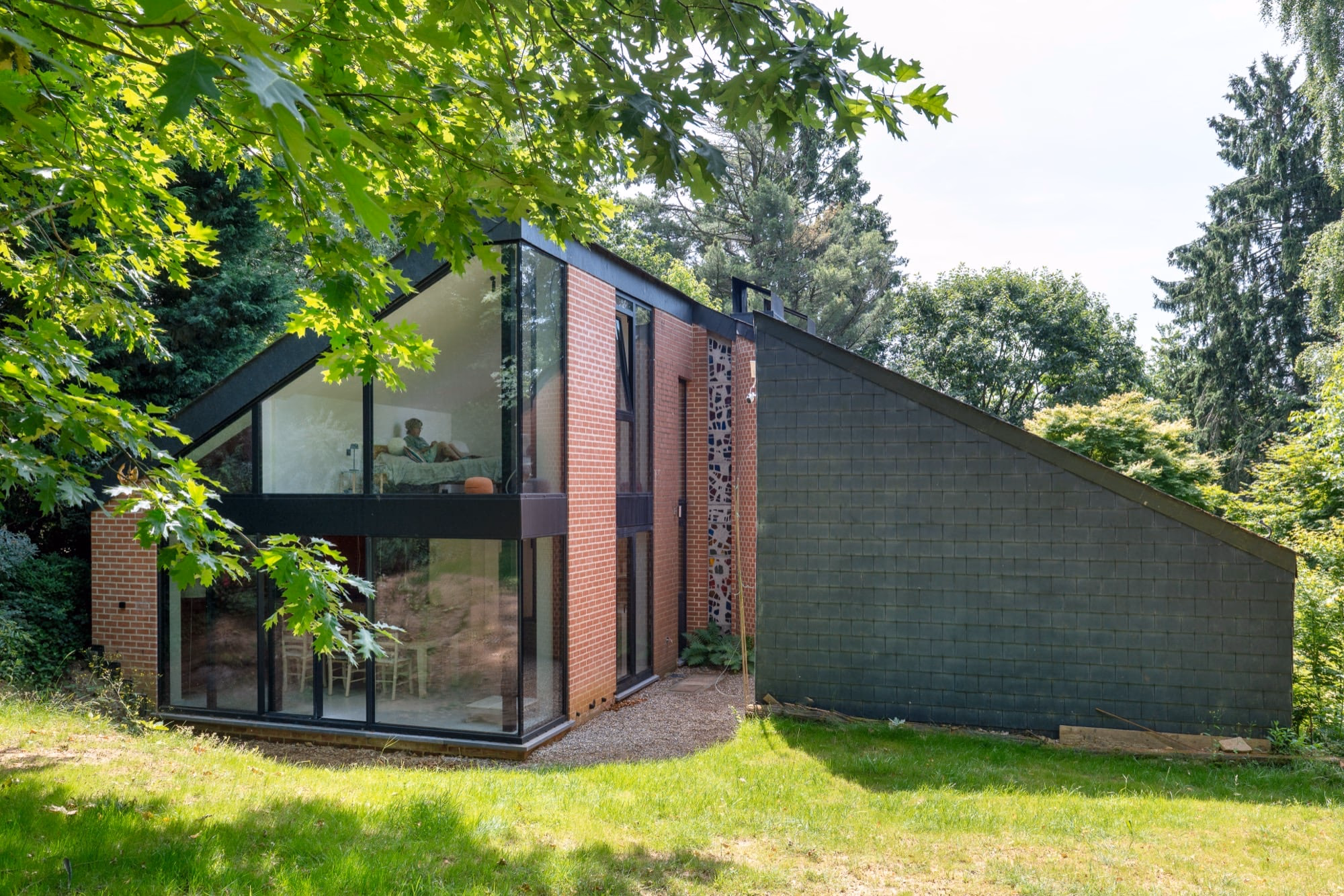 A brick house with a black-framed glass extension in a green garden