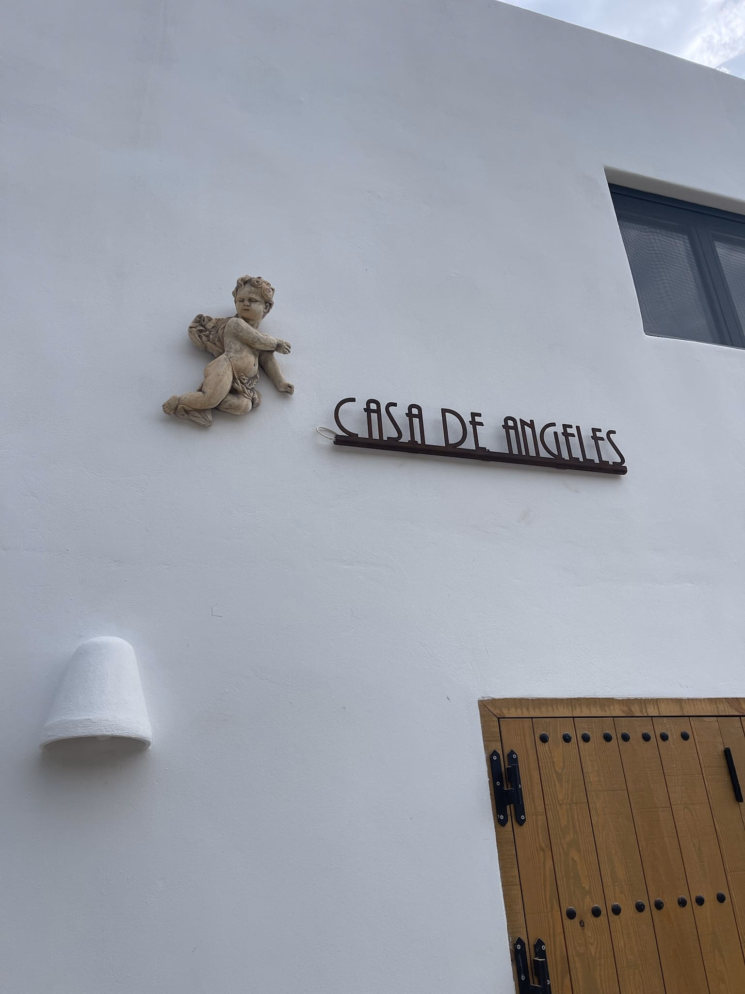 Mur blanc avec un ange décoratif et le nom de la maison, CASA DE ANGELES, au-dessus d’une porte en bois