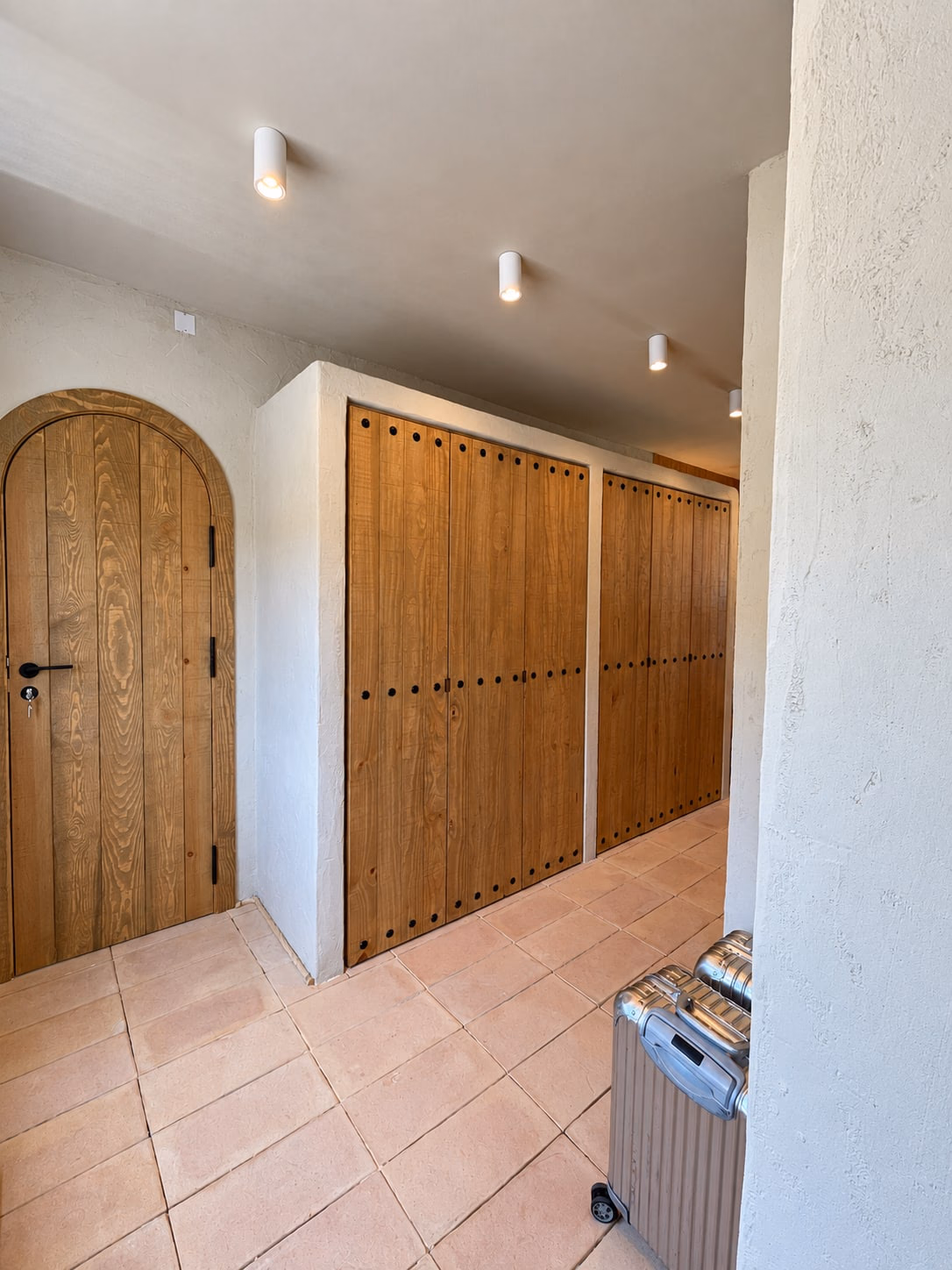 Couloir avec porte cintrée en chêne et hautes armoires en bois