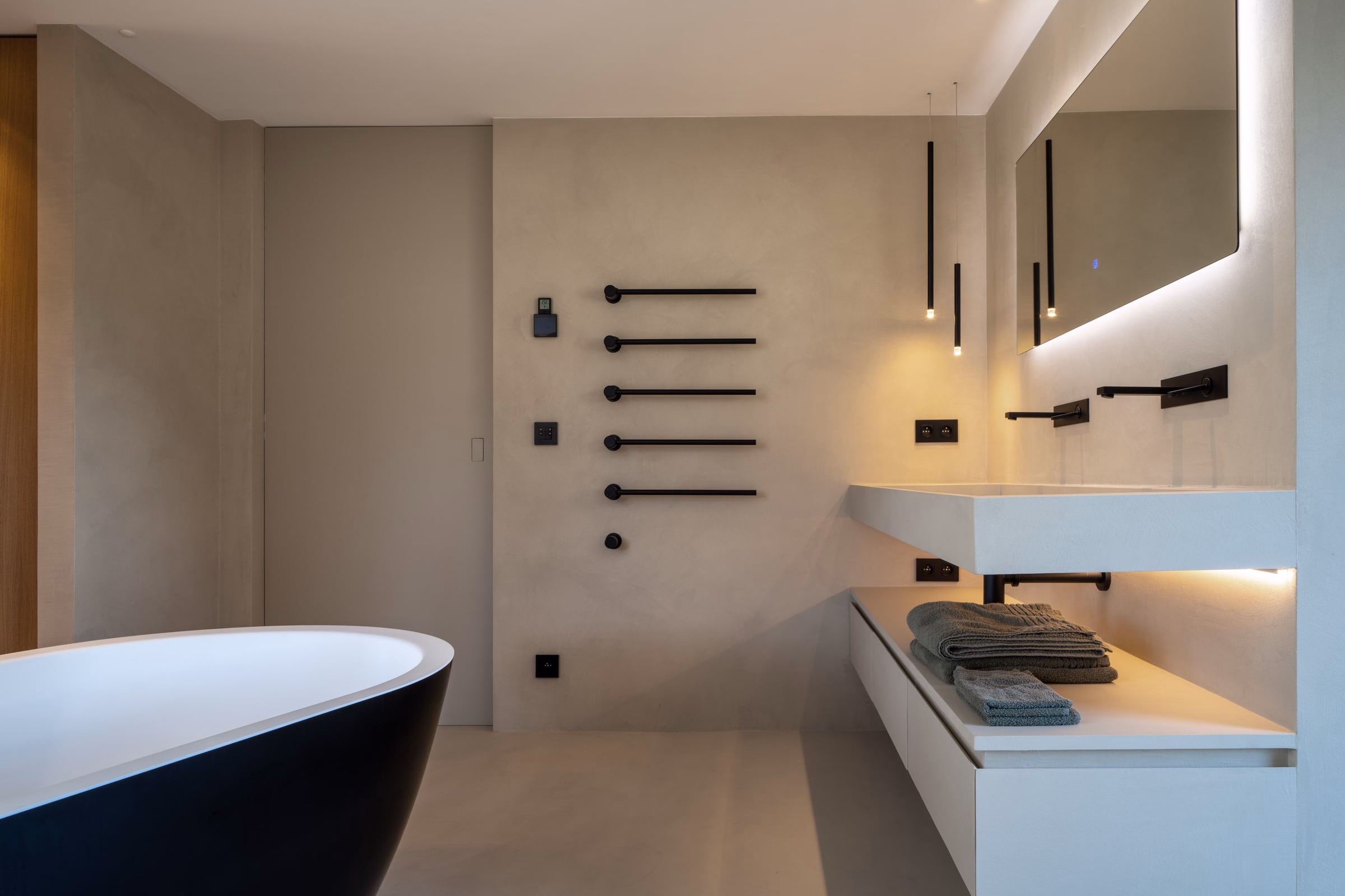 Bathroom with a black freestanding bath, wall-mounted towel bars and a floating vanity