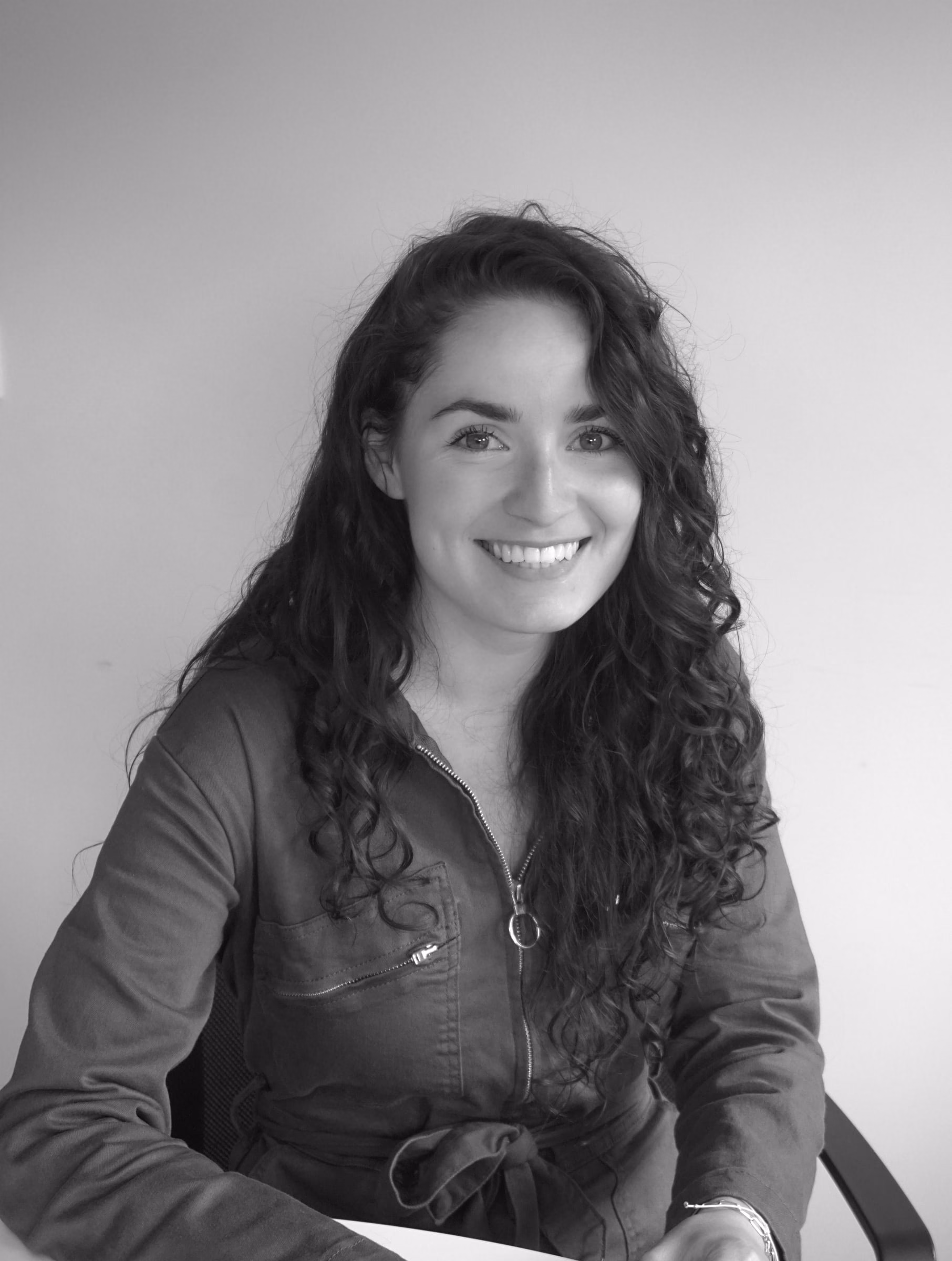 Black-and-white portrait of Prudence Vandecandelaere, smiling, seated at a desk