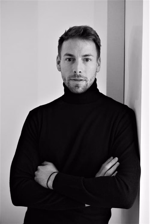 Black-and-white portrait of Rodolphe-Alexis Van Impe, arms crossed, in a black turtleneck